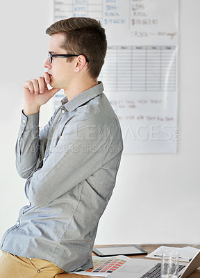 Buy stock photo Shot of a young male designer looking thoughtful in his office