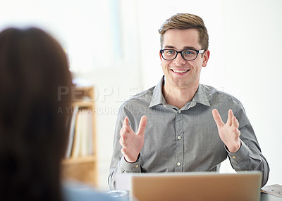 Buy stock photo Shot of a young male designer discussing work with a colleague