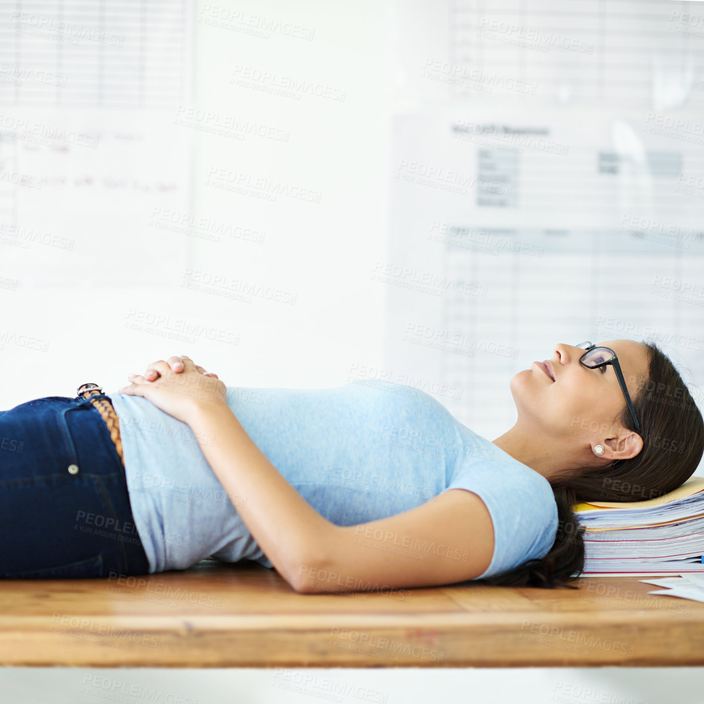 Buy stock photo Cropped shot of a smiling young businesswoman lying on her desk with paperwork on it