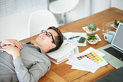 Buy stock photo Cropped shot of a male designer lying on his desk looking relieved