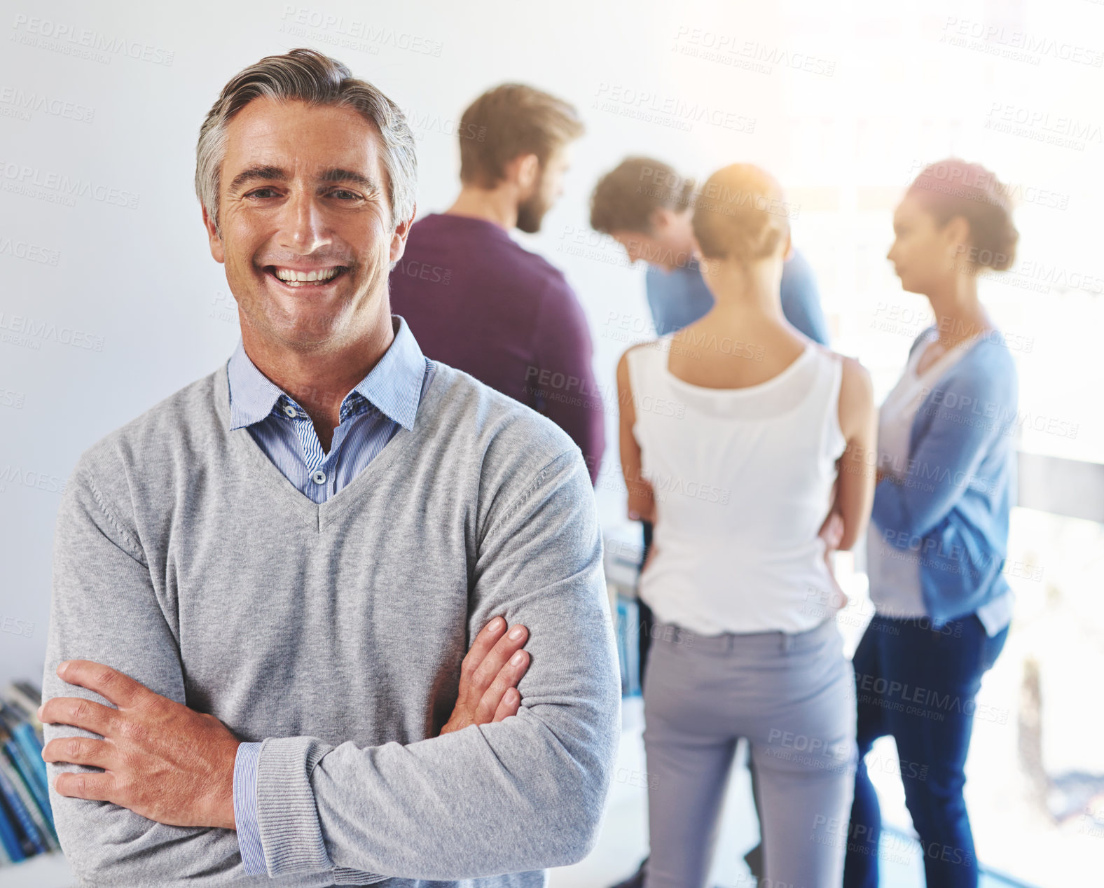 Buy stock photo Portrait of a mature businessman with his colleagues standing in the background