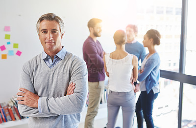 Buy stock photo Portrait of a mature businessman with his colleagues standing in the background