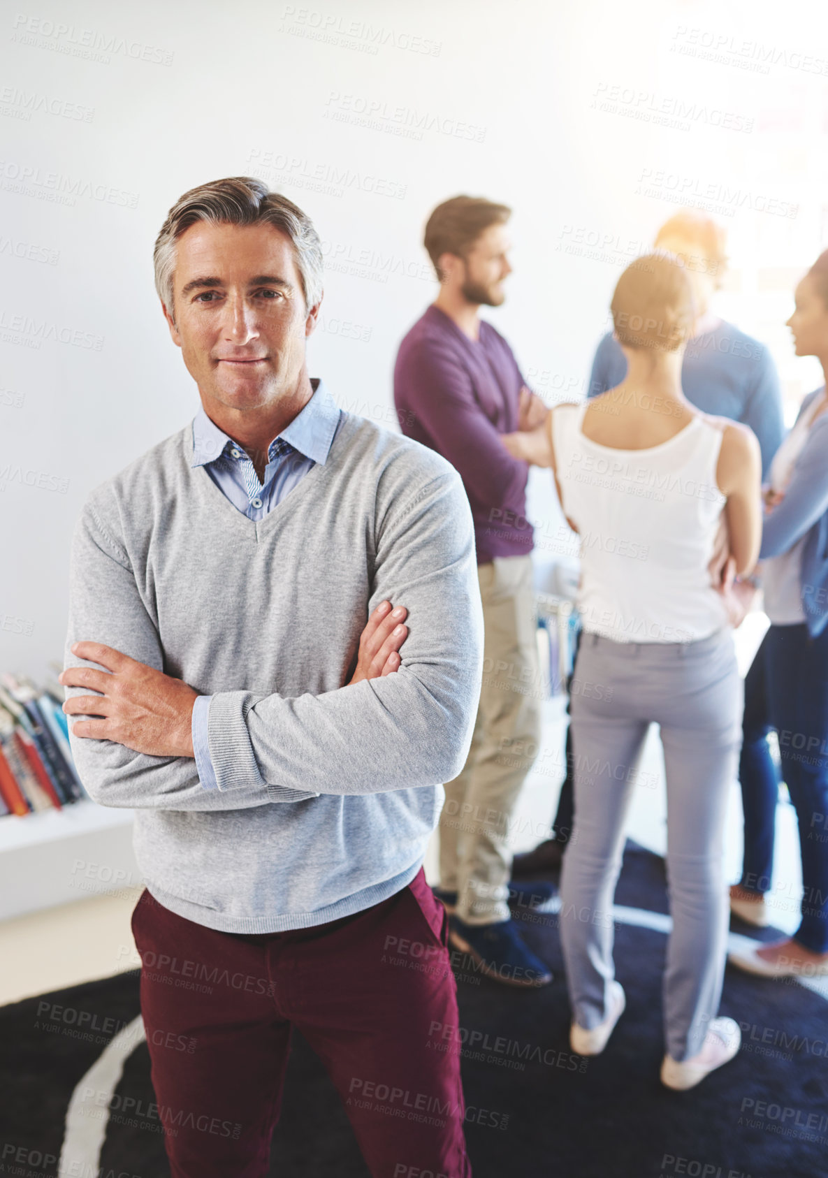 Buy stock photo Portrait of a mature businessman with his colleagues standing in the background