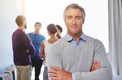 Buy stock photo Portrait of a mature businessman with his colleagues standing in the background