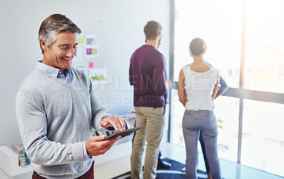 Buy stock photo Shot of a mature businessman using a digital tablet in an office setting