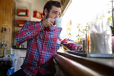 Buy stock photo Shot of a young man drinking a cup of coffee in a coffee shop