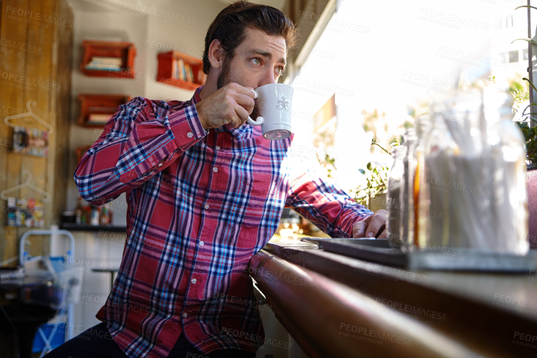 Buy stock photo Shot of a young man drinking a cup of coffee in a coffee shop