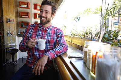 Buy stock photo Shot of a young man drinking a cup of coffee in a coffee shop