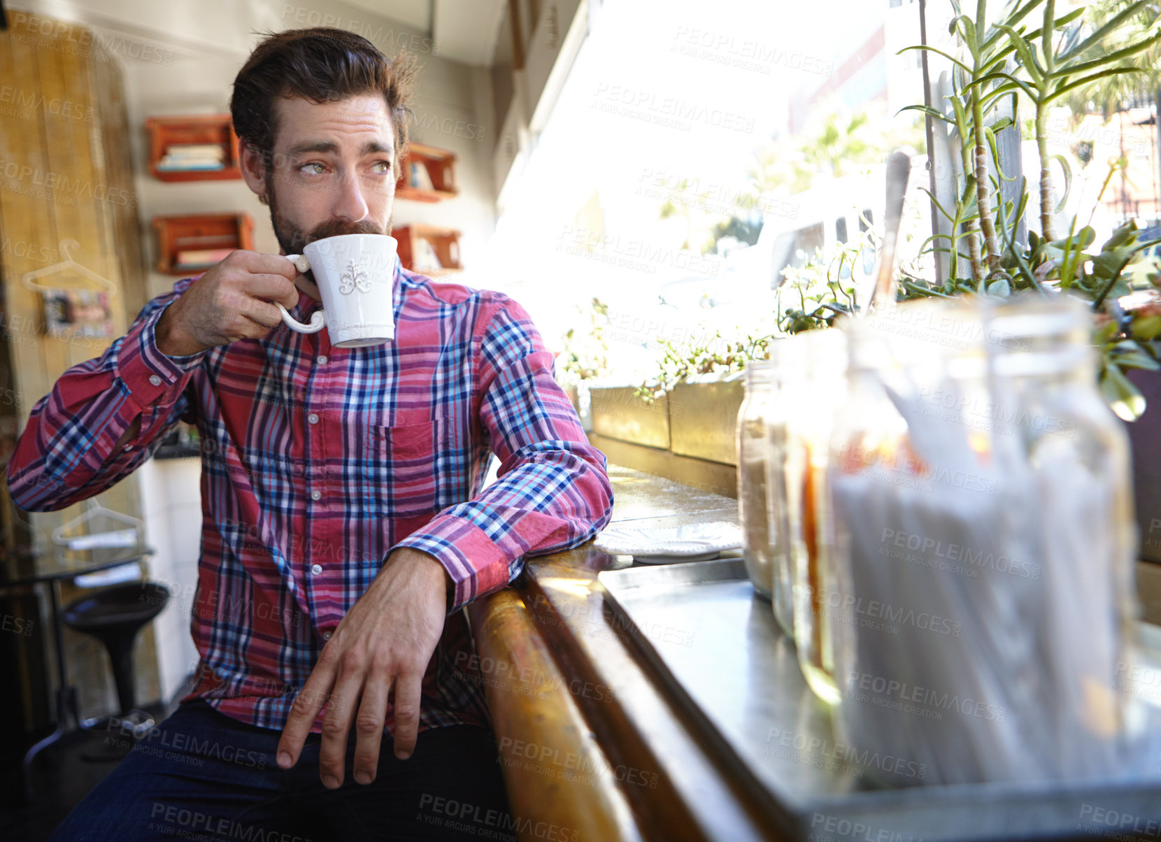 Buy stock photo Shot of a young man drinking a cup of coffee in a coffee shop