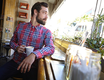 Buy stock photo Shot of a young man drinking a cup of coffee in a coffee shop