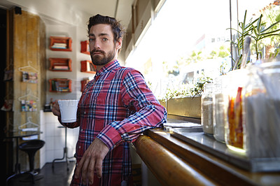 Buy stock photo Shot of a young man holding a cup of coffee in a cafe