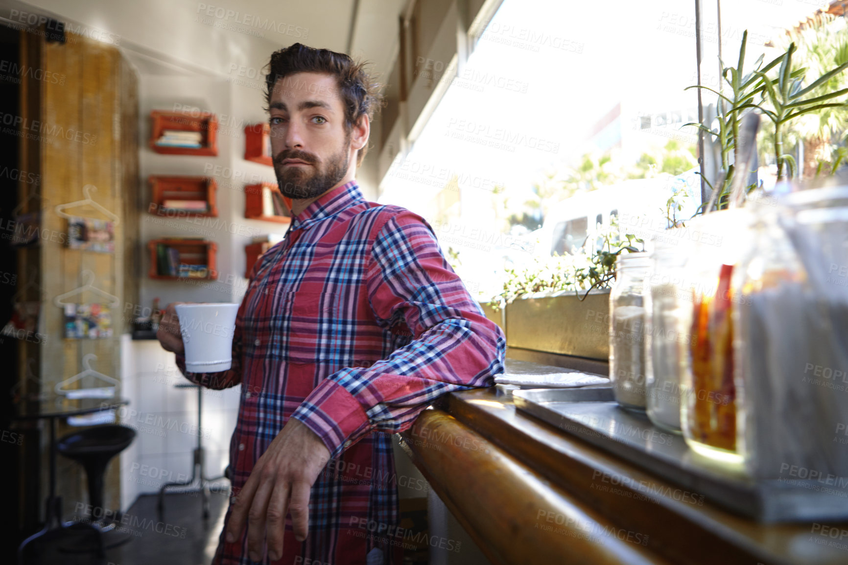 Buy stock photo Shot of a young man holding a cup of coffee in a cafe