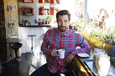 Buy stock photo Shot of a young man holding a cup of coffee in a cafe