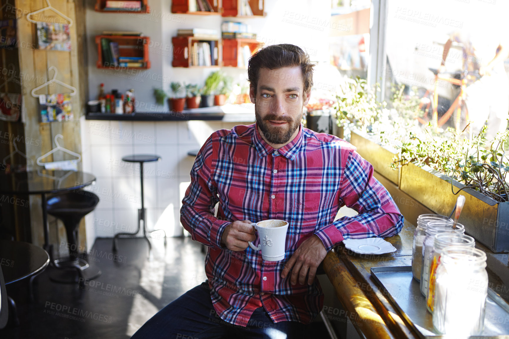 Buy stock photo Shot of a young man holding a cup of coffee in a cafe