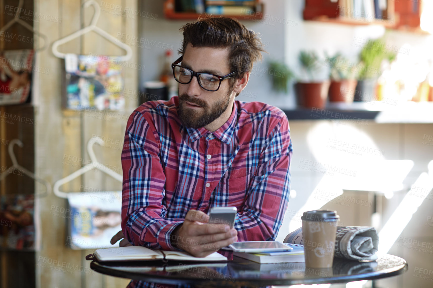 Buy stock photo Shot of a young man using his cellphone and digital tablet in a cafe