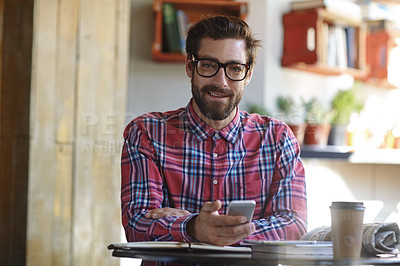 Buy stock photo Shot of a young man using his cellphone in a cafe