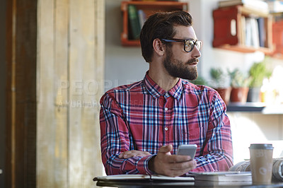 Buy stock photo Shot of a young man using his cellphone in a cafe