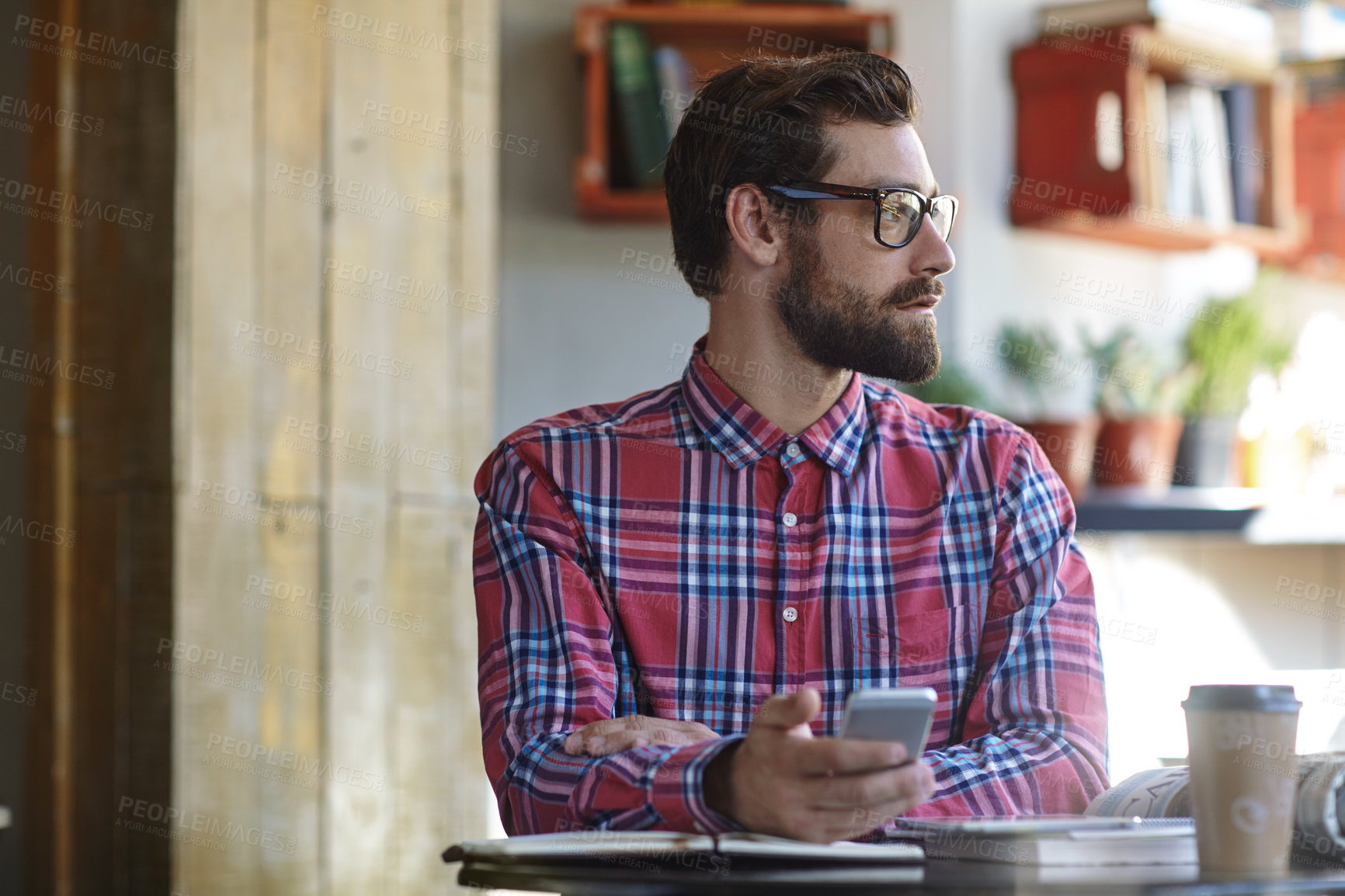 Buy stock photo Shot of a young man using his cellphone in a cafe