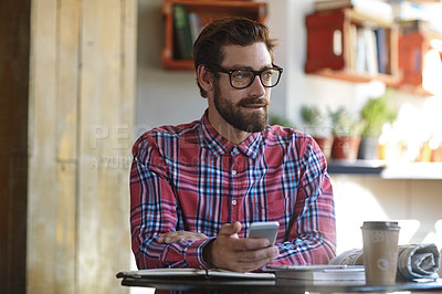 Buy stock photo Shot of a young man using his cellphone in a cafe