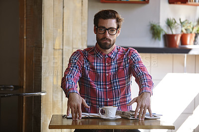 Buy stock photo Shot of a young man sitting at a table in a cafe