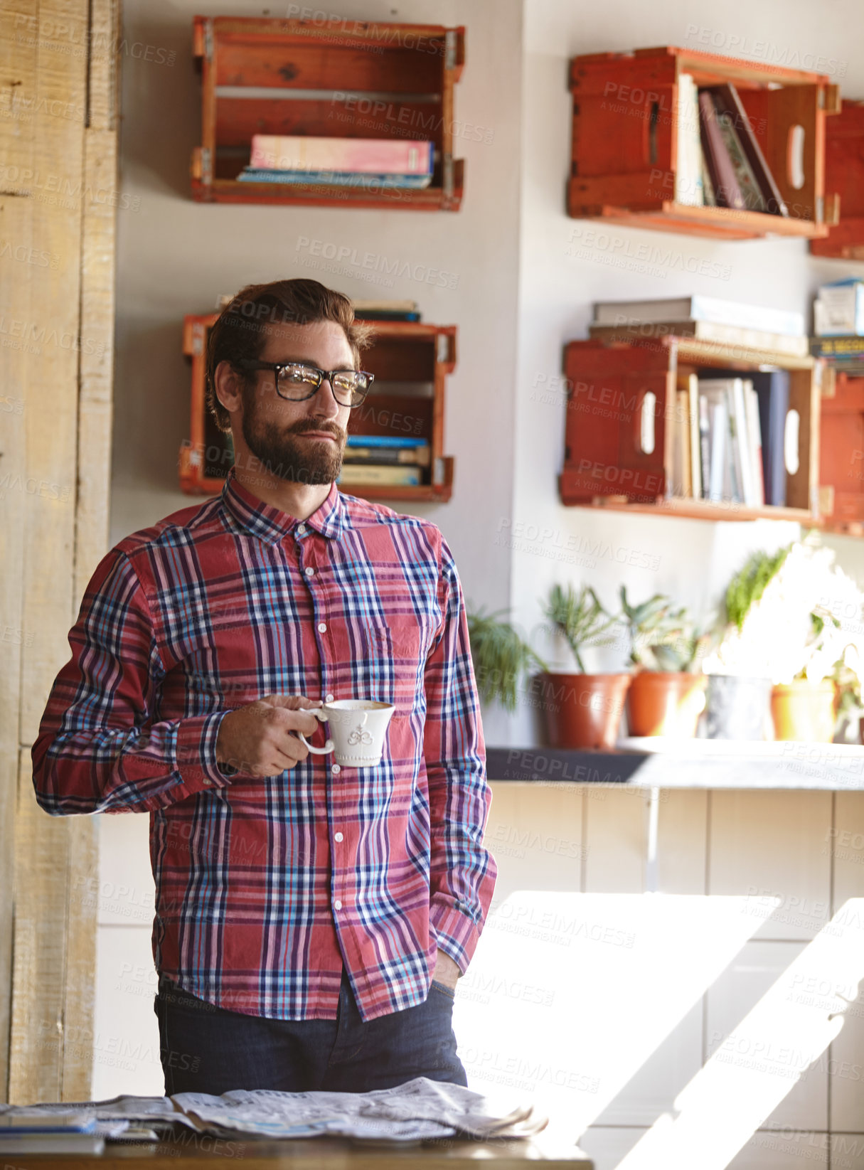 Buy stock photo Shot of a young man having coffee in a cafe with the newspaper lying on the table in front of him