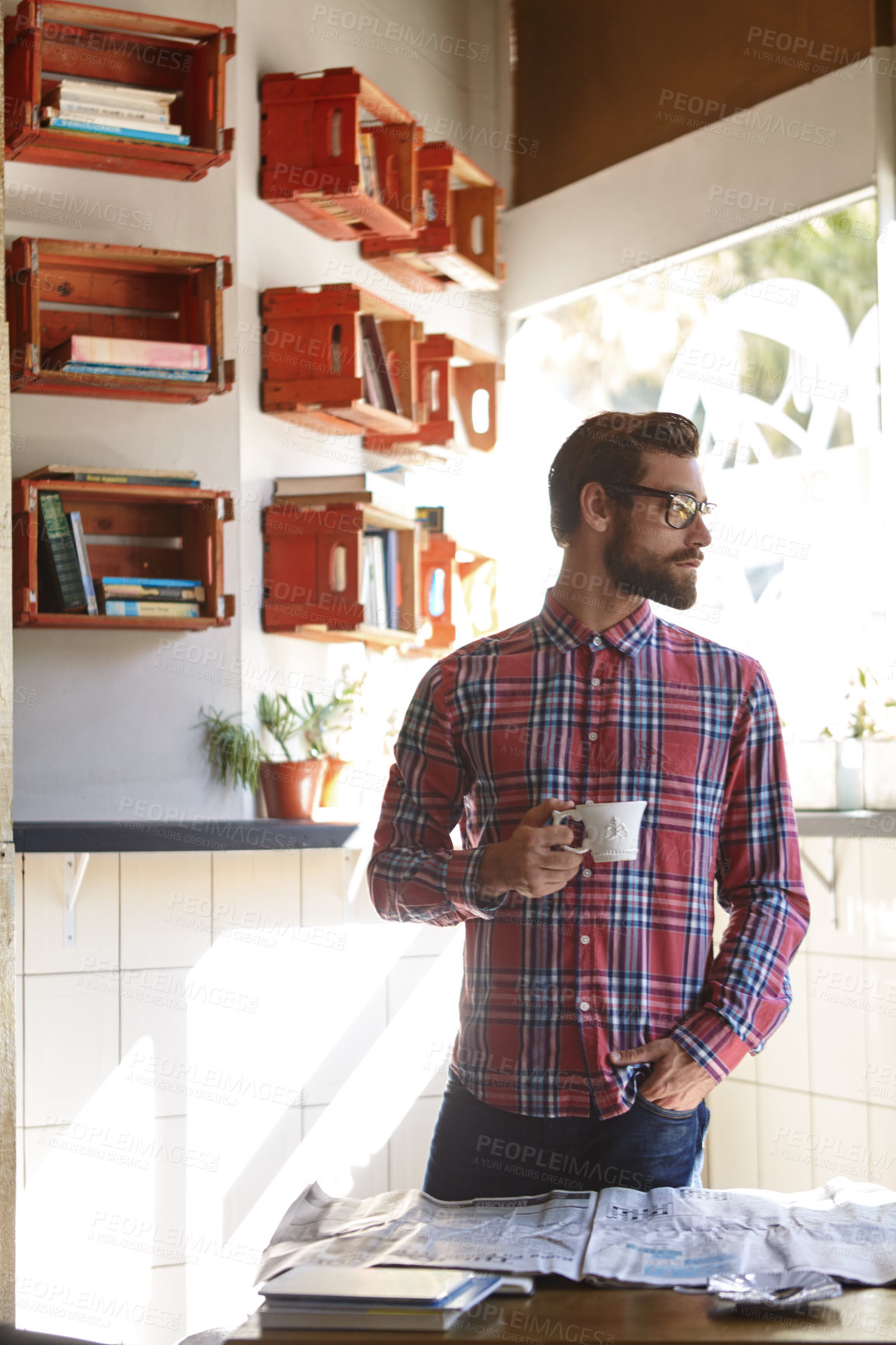 Buy stock photo Shot of a young man having coffee in a cafe with the newspaper lying on the table in front of him