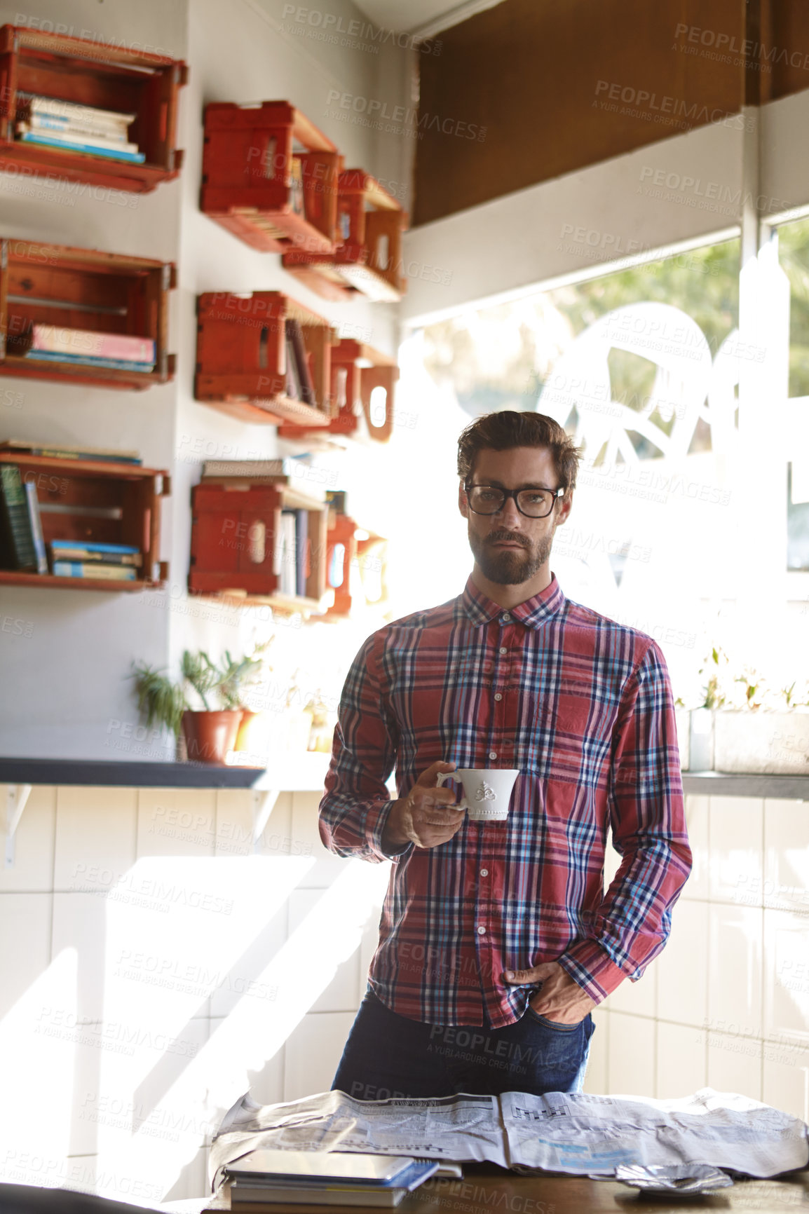 Buy stock photo Shot of a young man having coffee in a cafe with the newspaper lying on the table in front of him