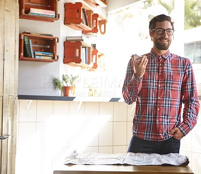 Buy stock photo Shot of a young man using his cellphone in a cafe with the newspaper lying in front of him