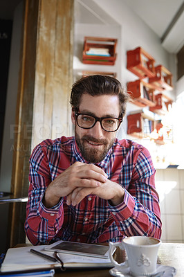 Buy stock photo Shot of a young man sitting in a coffee shop with his tablet and diary in front of him