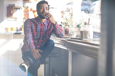 Buy stock photo Shot of a young man sitting in a coffee shop