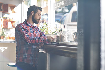 Buy stock photo Shot of a young man having a cup of coffee in a cafe