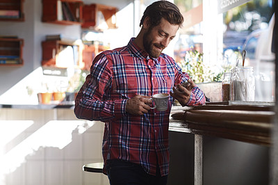 Buy stock photo Shot of a young man using his cellphone while sitting in a coffee shop