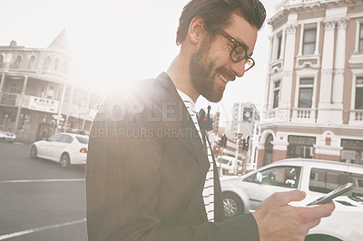 Buy stock photo Shot of a stylish young man using a cellphone while out in the city