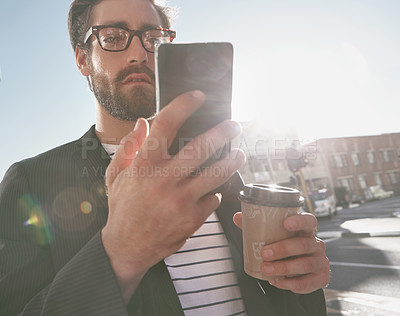 Buy stock photo Shot of a stylish young man using a cellphone while out in the city