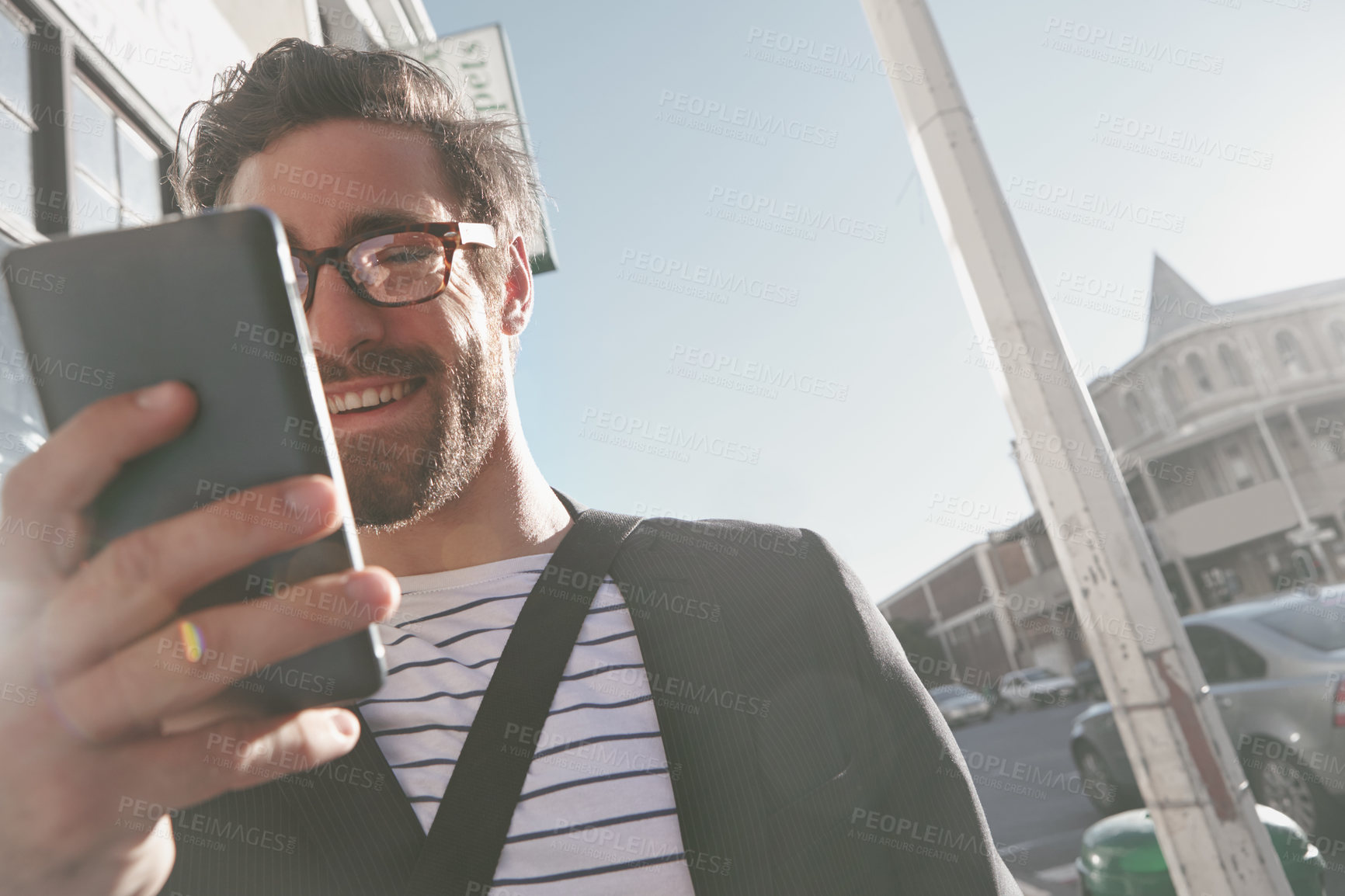 Buy stock photo Shot of a stylish young man using a cellphone while walking in the city