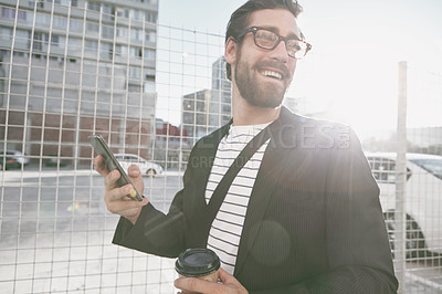 Buy stock photo Shot of a stylish young man using his cellphone while out walking in the city