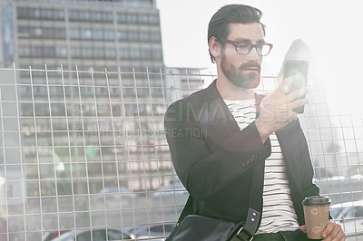 Buy stock photo Shot of a stylish young man using a cellphone while out in the city