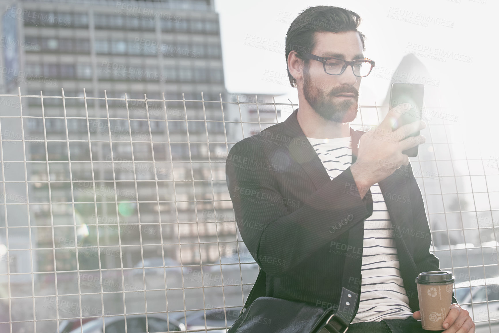 Buy stock photo Shot of a stylish young man using a cellphone while out in the city