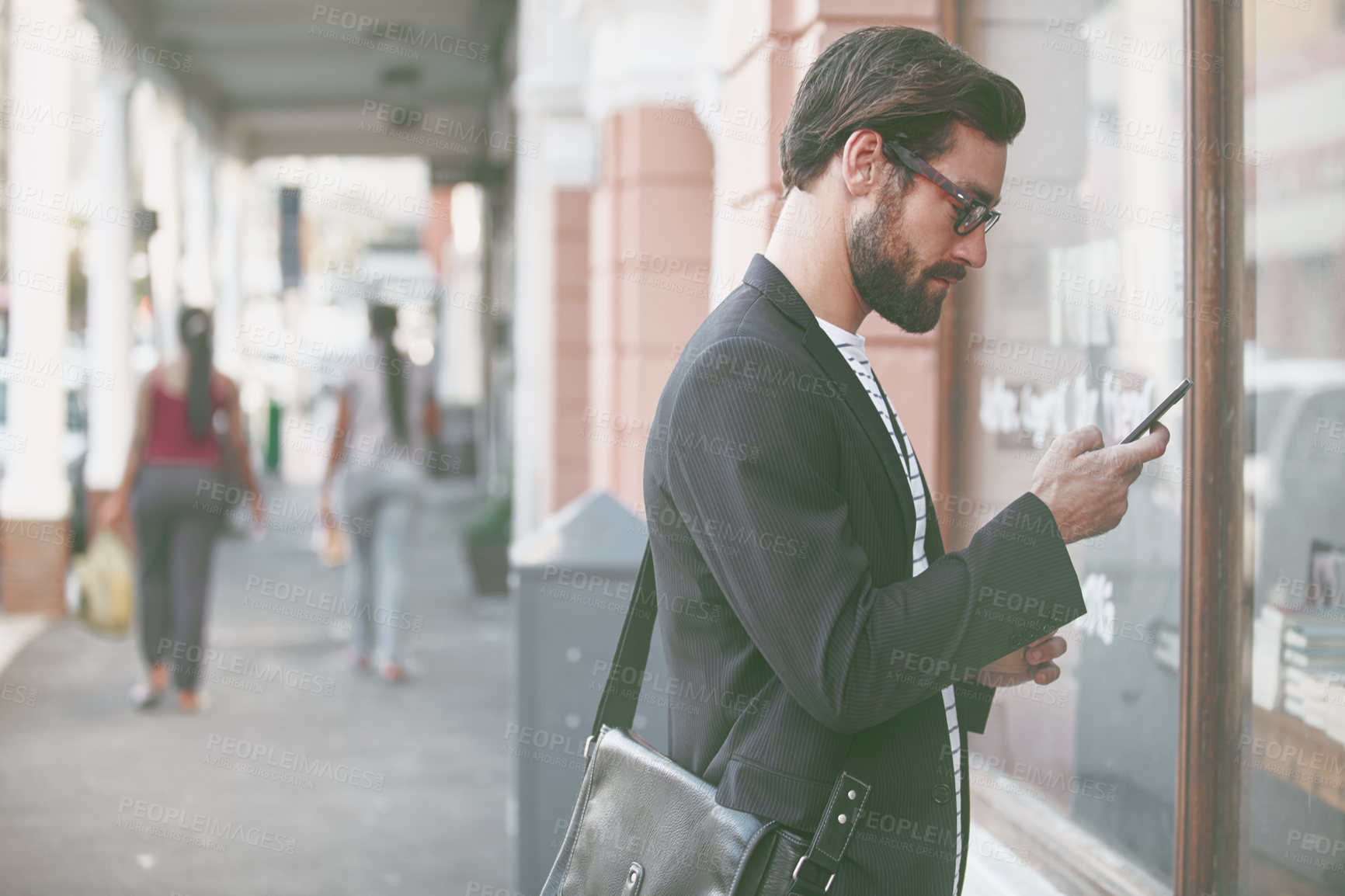 Buy stock photo Shot of a stylish young man using a cellphone while out in the city