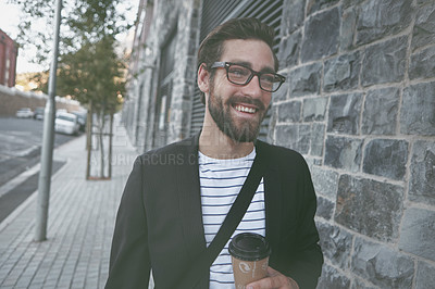 Buy stock photo Shot of a young man having a coffee on the go while out walking in the city