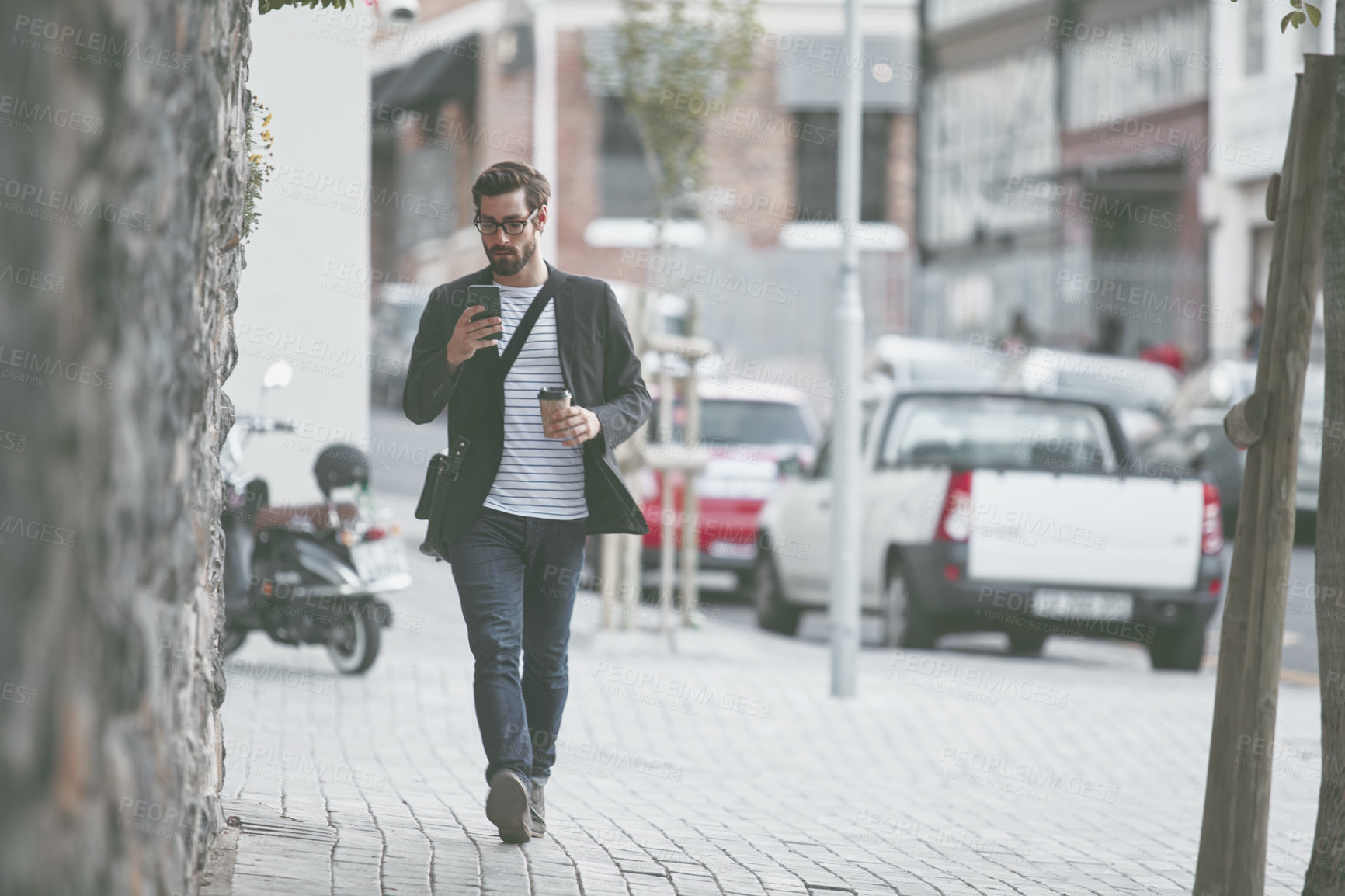 Buy stock photo Shot of a stylish young man using a cellphone while out walking in the city