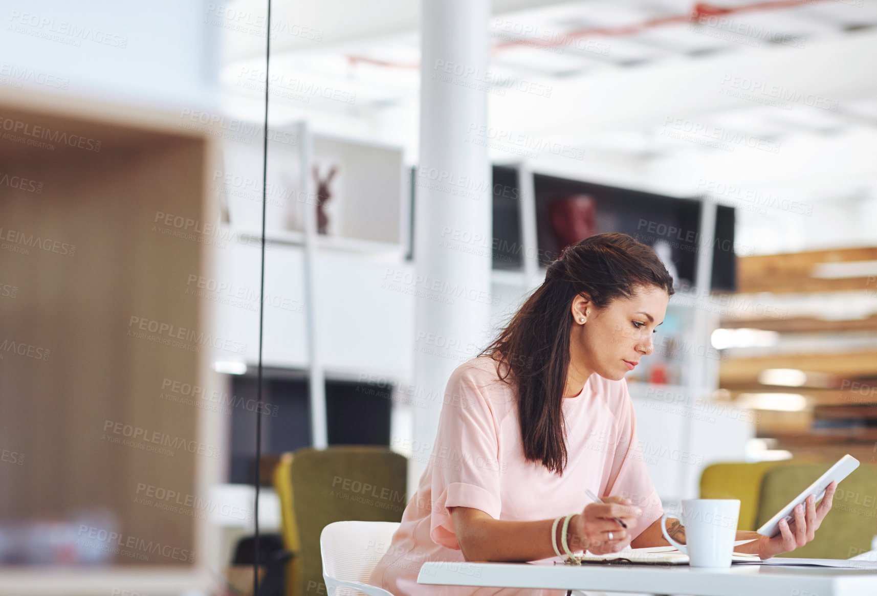 Buy stock photo Cropped shot of a young businsswoman using a digital tablet at her desk in the office