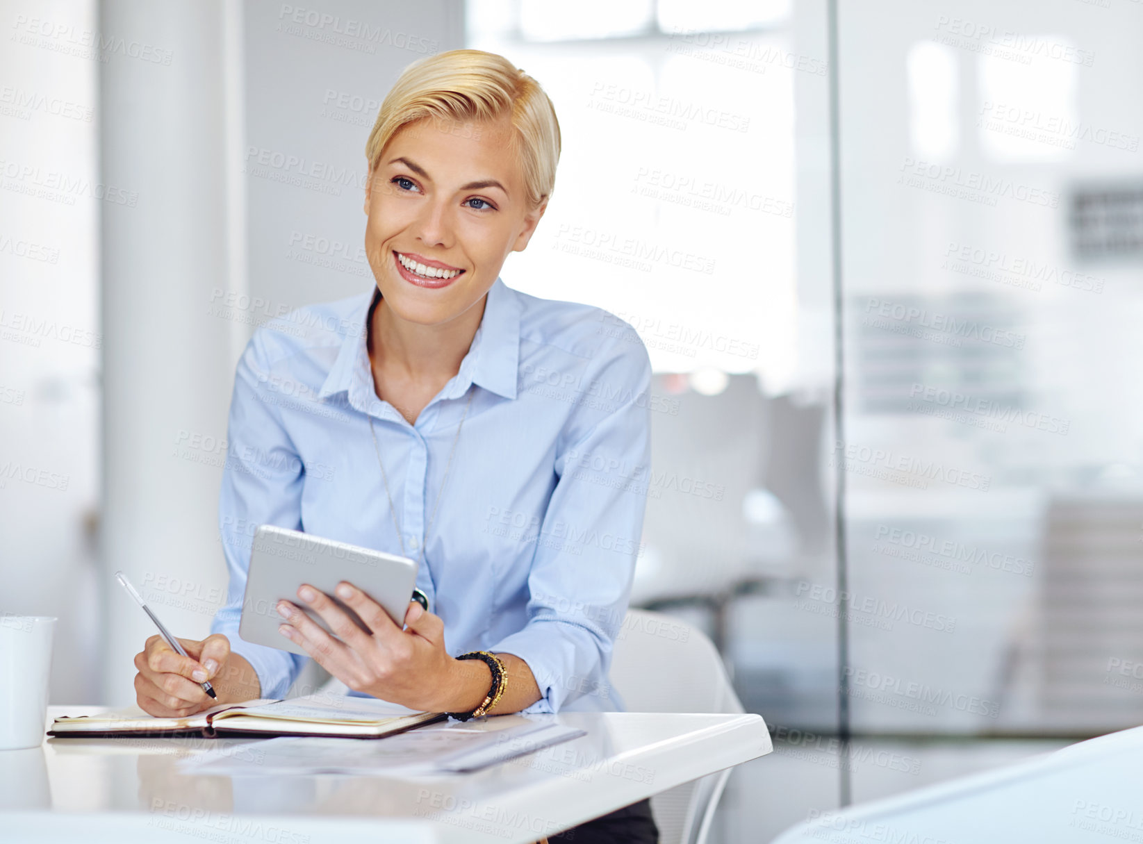 Buy stock photo Cropped shot of a young businsswoman using a digital tablet at her desk in the office