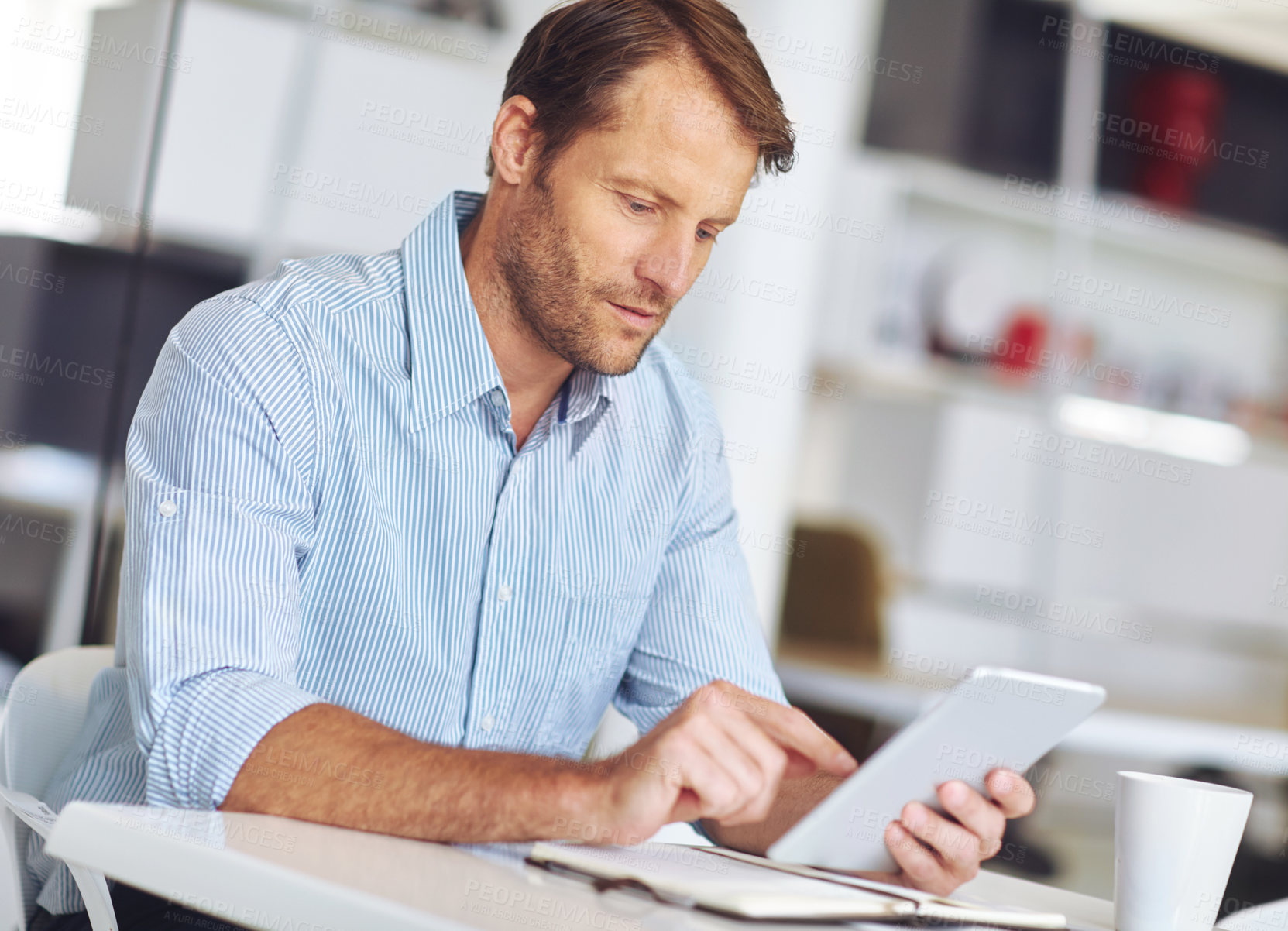 Buy stock photo Cropped shot of a mature businssman using a digital tablet at his desk in the office