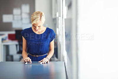 Buy stock photo Cropped shot of a young businesswoman working on her tablet in the office