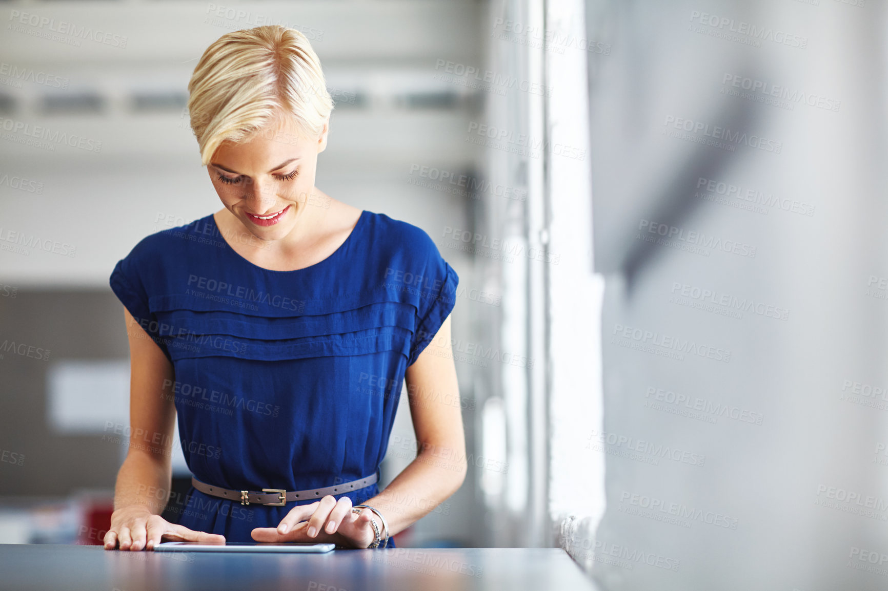 Buy stock photo Cropped shot of a young businesswoman working on her tablet in the office