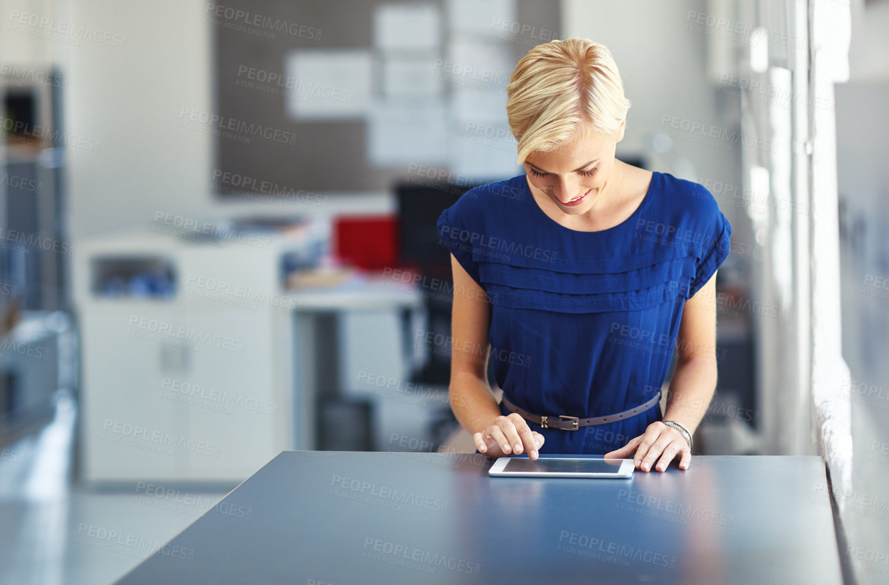 Buy stock photo Cropped shot of a young businesswoman working on her tablet in the office