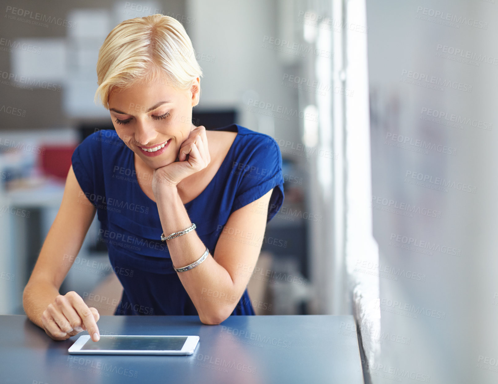 Buy stock photo Cropped shot of a young businesswoman working on her tablet in the office