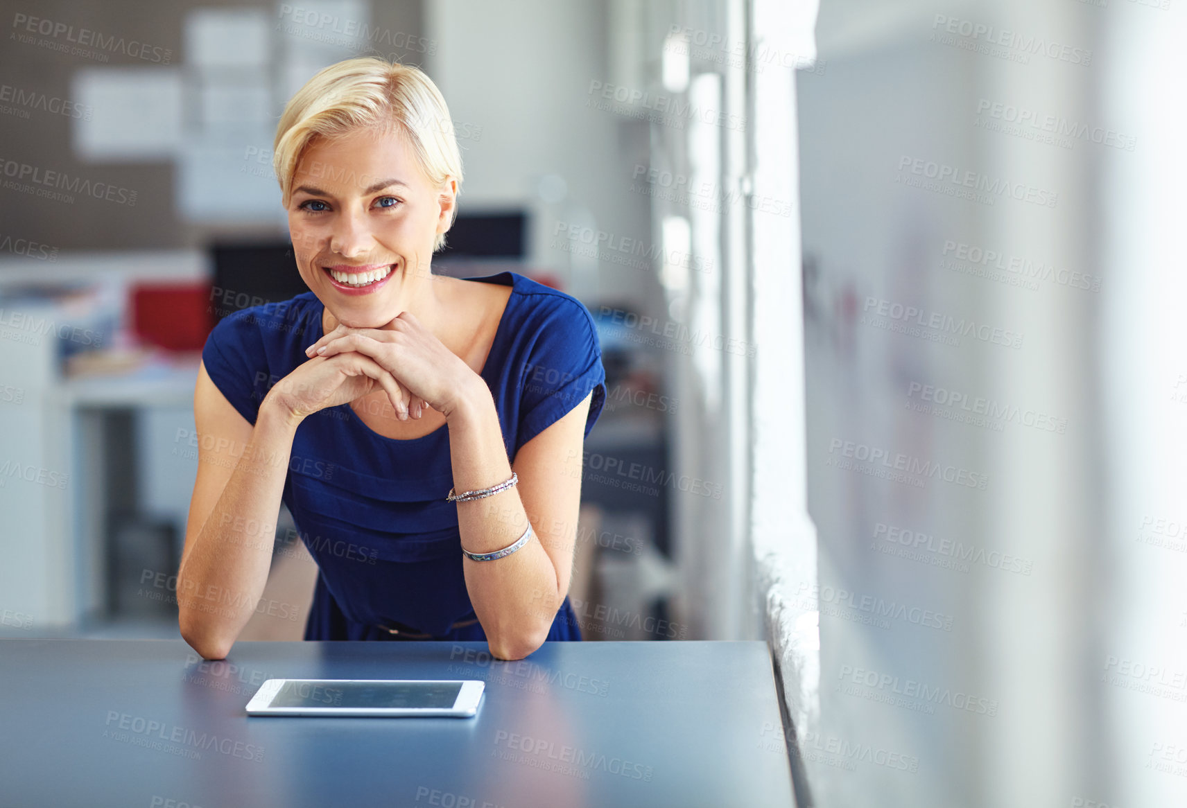 Buy stock photo Cropped portrait of a young businesswoman working on her tablet in the office