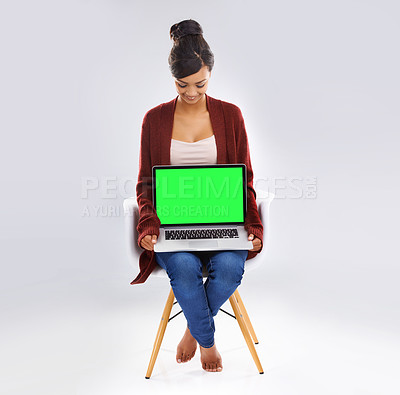 Buy stock photo Studio portrait of an attractive young woman sitting on a chair holding a laptop